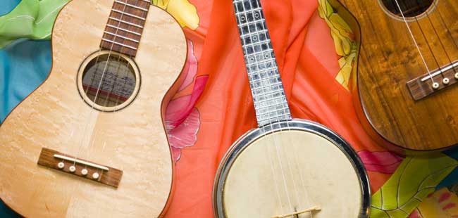 Deb's Three Ukuleles — one made from blond wood, another (a silver-colored Dixie Banjo-Uke) made of metal, and a third of dark walnut.